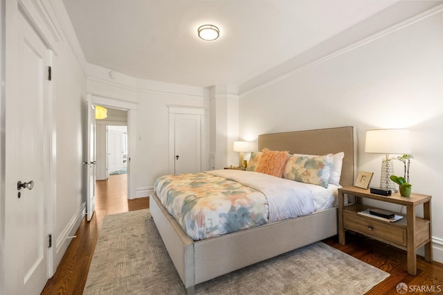 bedroom featuring crown molding, baseboards, and wood finished floors