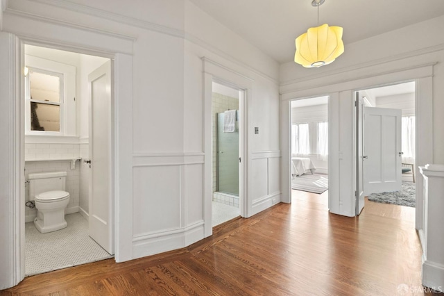 corridor featuring a wainscoted wall and wood finished floors