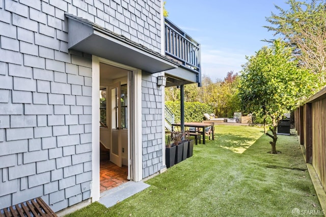 view of yard with a balcony and fence