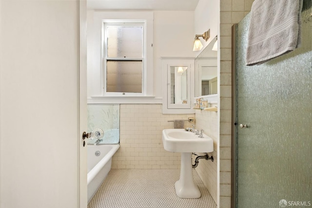 bathroom featuring a sink, tile patterned flooring, a bathtub, and tile walls