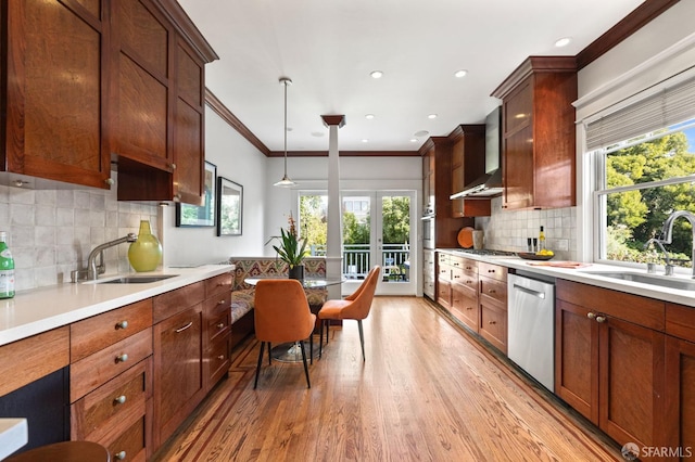 kitchen featuring wall chimney range hood, stainless steel appliances, a sink, and light wood finished floors