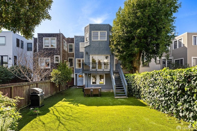 rear view of property with fence, stairway, a deck, and a yard