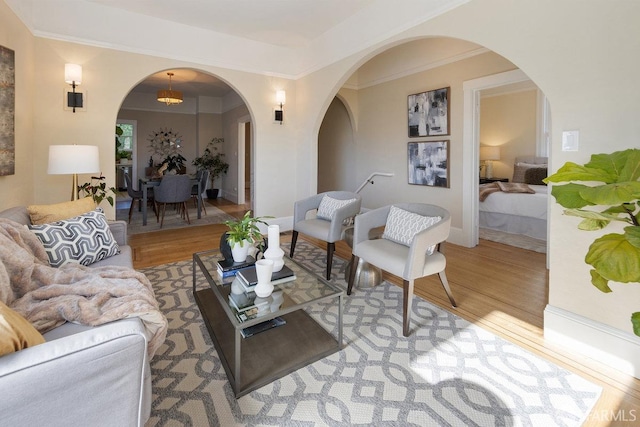 living room featuring ornamental molding, an inviting chandelier, and light hardwood / wood-style flooring