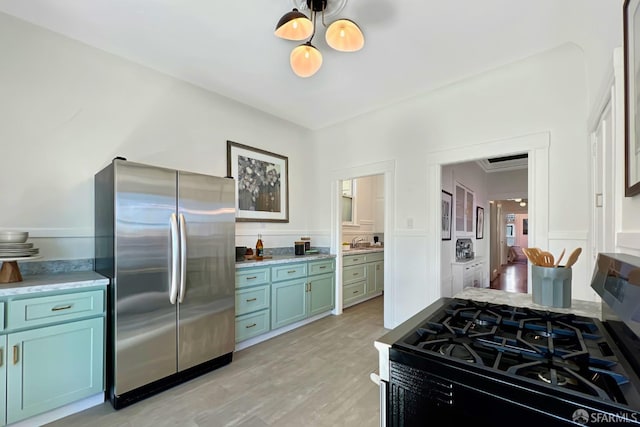 kitchen with gas range, sink, stainless steel fridge, and light hardwood / wood-style floors