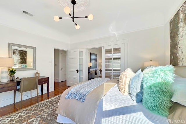 bedroom with dark wood-type flooring, an inviting chandelier, and french doors