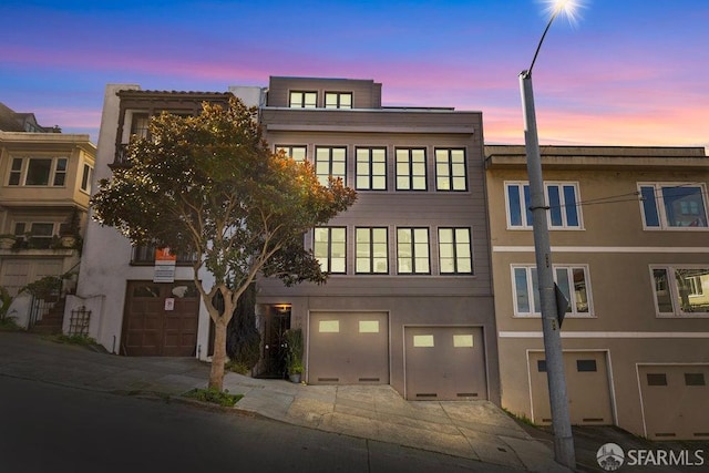 property at dusk featuring a garage