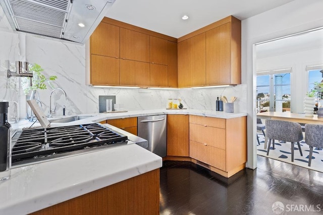 kitchen featuring dark wood finished floors, decorative backsplash, extractor fan, light countertops, and appliances with stainless steel finishes