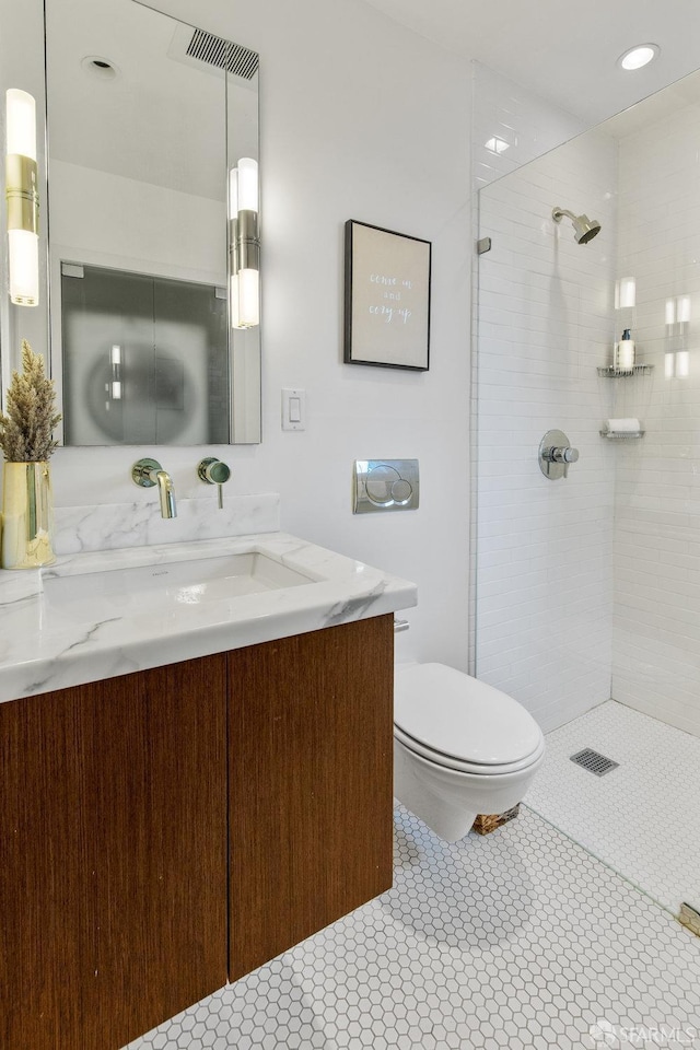 bathroom with visible vents, toilet, tiled shower, tile patterned floors, and vanity