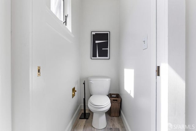 bathroom featuring baseboards, toilet, and wood finished floors