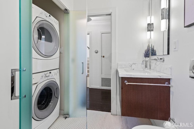 laundry room with laundry area, stacked washing maching and dryer, and a sink