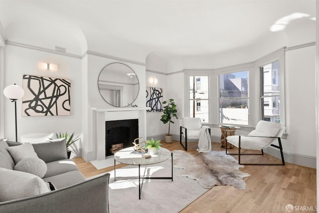 living room with light wood-style floors, visible vents, a fireplace, and baseboards