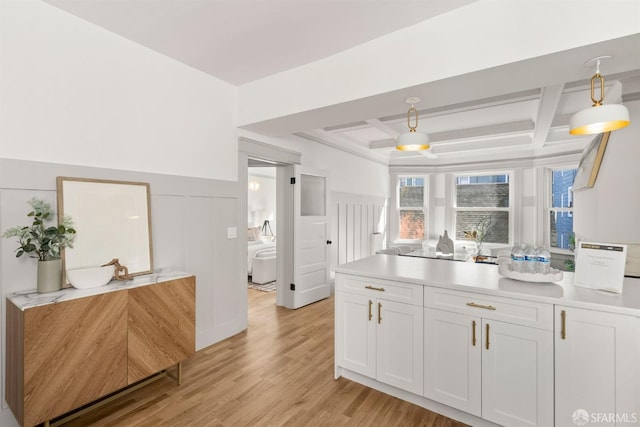 kitchen featuring light countertops, coffered ceiling, light wood finished floors, and white cabinetry