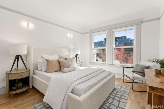 bedroom featuring a city view, light wood-style flooring, and crown molding