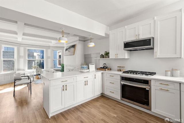 kitchen with a peninsula, light wood-style flooring, stainless steel appliances, and light countertops