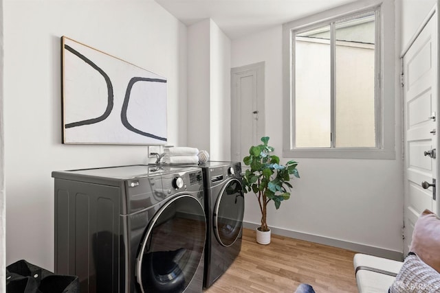 laundry room featuring laundry area, baseboards, separate washer and dryer, and wood finished floors