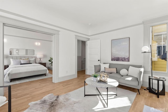 bedroom with ornamental molding, wood finished floors, and baseboards