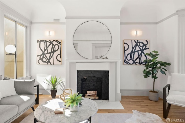 living room with baseboards, a fireplace with flush hearth, visible vents, and wood finished floors