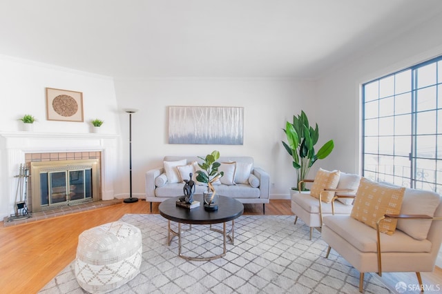 living room featuring crown molding, light hardwood / wood-style floors, and a tile fireplace