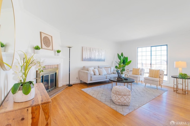 living room featuring a brick fireplace, crown molding, and light hardwood / wood-style floors