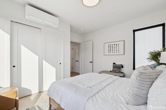 bedroom with light wood-type flooring, a closet, and a wall unit AC