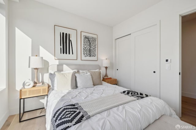 bedroom with light wood-style floors, a closet, and baseboards