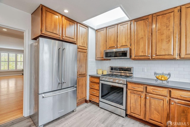 kitchen featuring appliances with stainless steel finishes, brown cabinetry, and backsplash