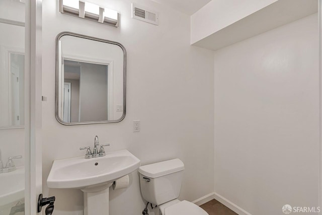 bathroom with baseboards, visible vents, a sink, and toilet