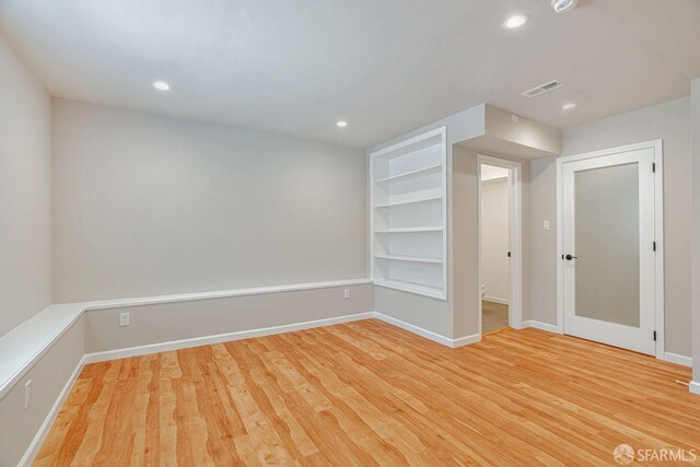 spare room featuring baseboards, visible vents, built in features, light wood-type flooring, and recessed lighting