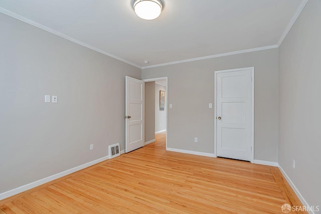 empty room with visible vents, crown molding, light wood-style flooring, and baseboards