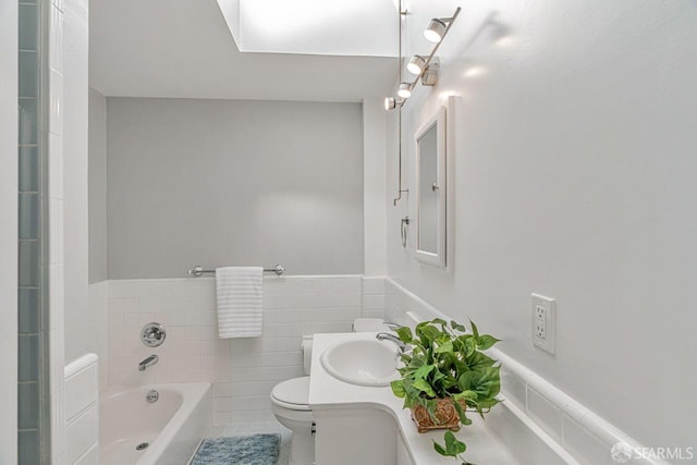 full bathroom featuring tile walls, toilet, wainscoting, a tub, and tile patterned flooring