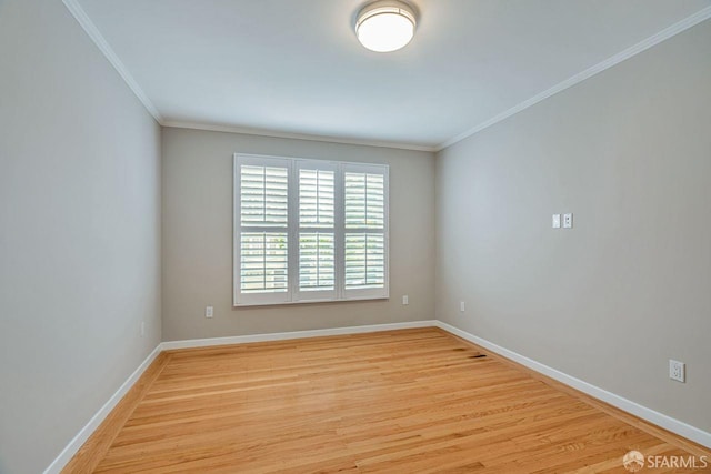 spare room with crown molding, light wood-type flooring, and baseboards