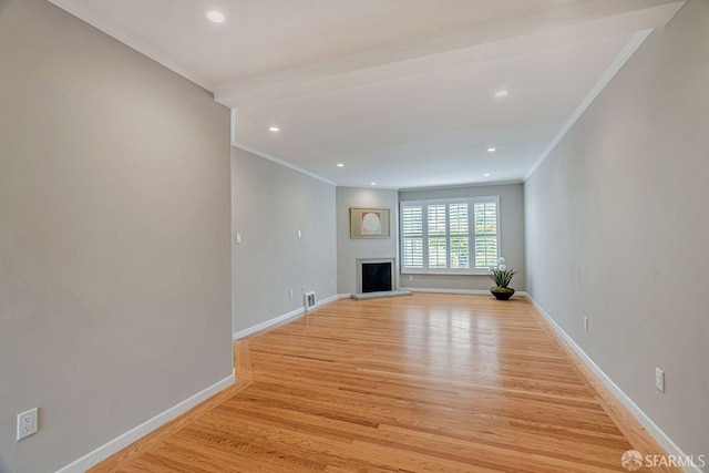 unfurnished living room with light wood-type flooring, baseboards, a fireplace with raised hearth, and ornamental molding