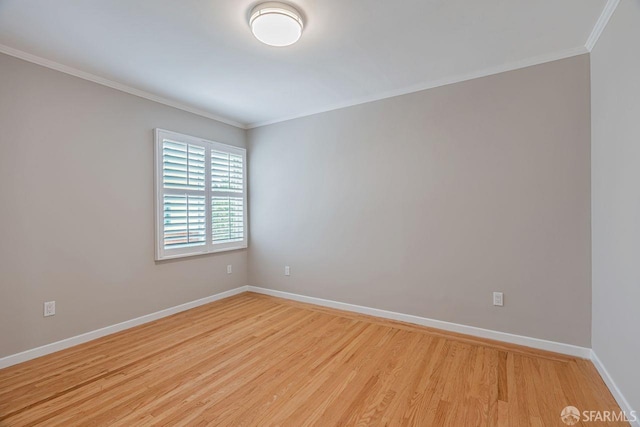 empty room with light wood finished floors, baseboards, and ornamental molding