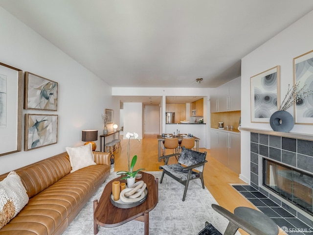 living area with a tile fireplace and light wood finished floors