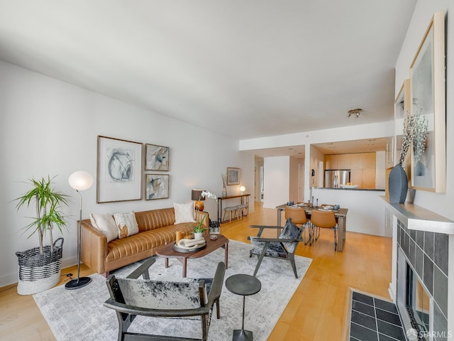 living area featuring light wood-style floors and a tile fireplace