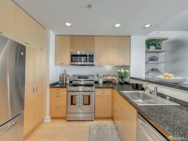 kitchen featuring appliances with stainless steel finishes, light wood-type flooring, light brown cabinets, and a sink