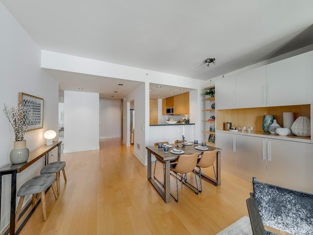 kitchen featuring light wood-style floors, white cabinets, stainless steel microwave, and open shelves