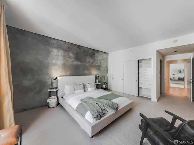 bedroom featuring carpet, an accent wall, and a closet