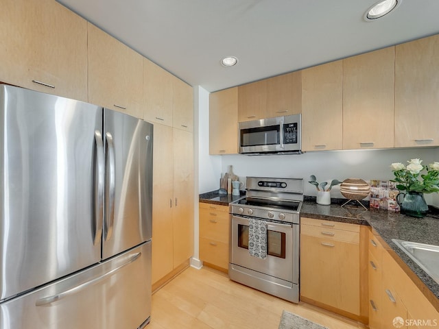 kitchen with light brown cabinetry, appliances with stainless steel finishes, and dark countertops