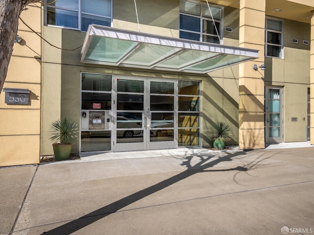 entrance to property featuring french doors and stucco siding