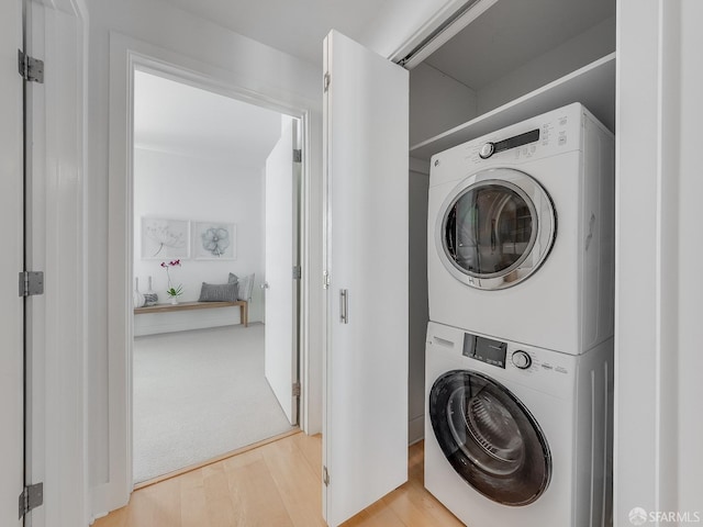 clothes washing area featuring stacked washer and dryer, laundry area, and wood finished floors