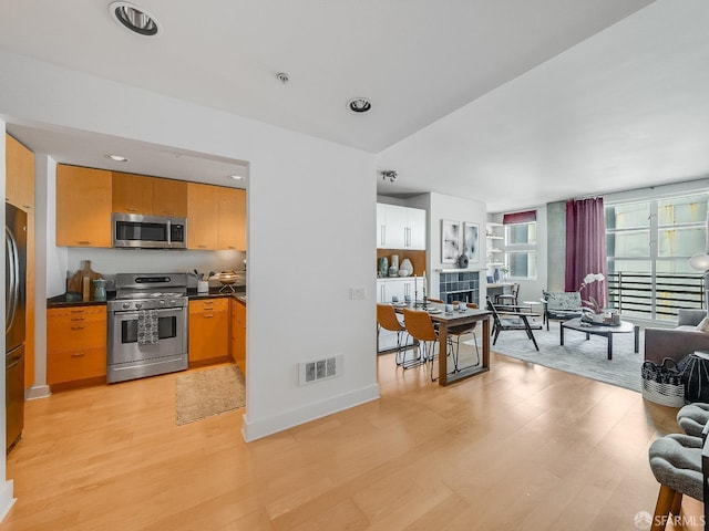 kitchen featuring dark countertops, light wood-type flooring, visible vents, and stainless steel appliances