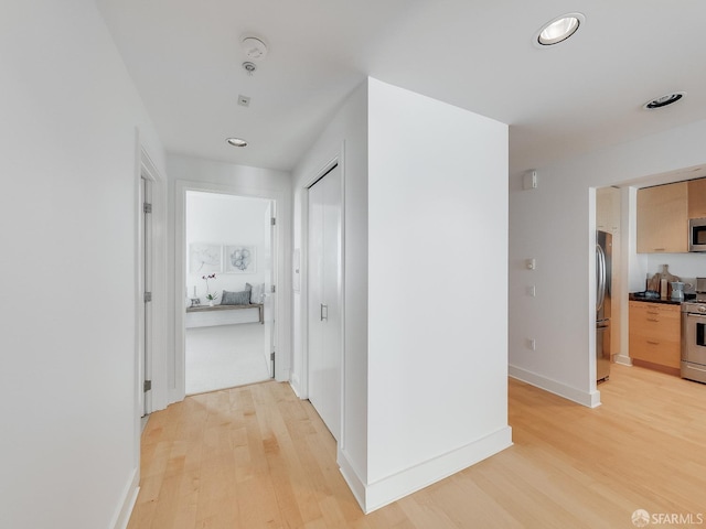 hallway with recessed lighting, light wood-style flooring, and baseboards