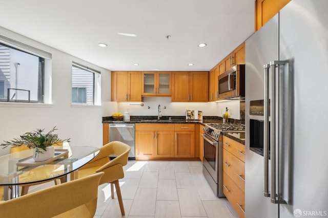 239 8th St Unit 14, San Francisco, CA 94103 - kitchen featuring appliances with stainless steel finishes, a sink, glass insert cabinets, brown cabinets, and recessed lighting