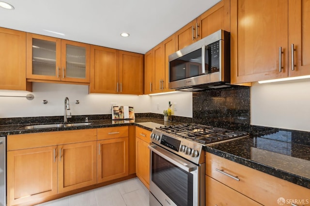 239 8th St Unit 14, San Francisco, CA 94103 - kitchen with appliances with stainless steel finishes, a sink, recessed lighting, dark stone countertops, and brown cabinets