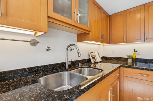 239 8th St Unit 14, San Francisco, CA 94103 - kitchen with a sink, glass insert cabinets, brown cabinetry, and dark stone counters