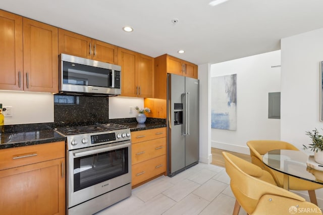 239 8th St Unit 14, San Francisco, CA 94103 - kitchen with stainless steel appliances, recessed lighting, brown cabinetry, tasteful backsplash, and dark stone countertops