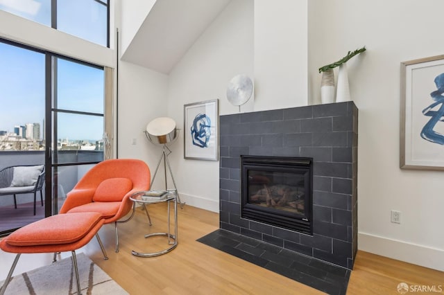 239 8th St Unit 14, San Francisco, CA 94103 - living area featuring wood finished floors, baseboards, a tiled fireplace, and a high ceiling