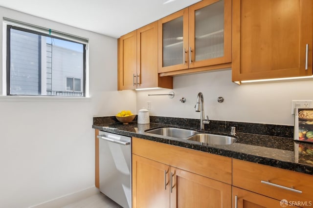 239 8th St Unit 14, San Francisco, CA 94103 - kitchen featuring dishwasher, a sink, dark stone counters, glass insert cabinets, and baseboards