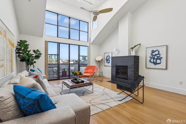 239 8th St Unit 14, San Francisco, CA 94103 - living area with a high ceiling, a fireplace with flush hearth, baseboards, wood finished floors, and a ceiling fan